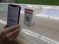 窓口に置かれているPayPayのQRコードをスマホで読み取ろうとしている様子の写真
