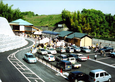 駐車場に沢山の車が停まっており、多くの人達で賑わっている道の駅かなんの写真