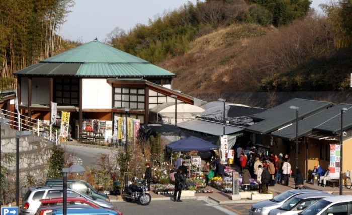 駐車場に沢山の車が停まり、建物の前に大勢のお客さんが集まり賑わっている道の駅かなんの写真