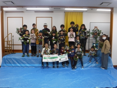 完成したクリスマスリースを手に持って参加した子供たちが記念撮影をしている写真