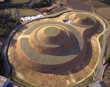 大小二つの円丘が連結した形の双円墳の金山古墳を上空から撮影した写真
