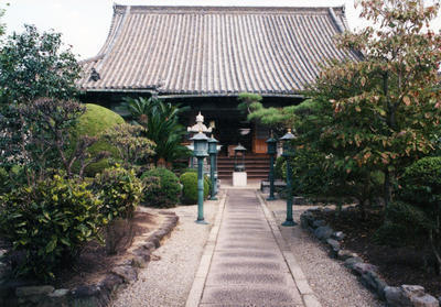 寺の本堂に続く道の両側に灯籠が立っており、木々に囲まれた大念寺の写真