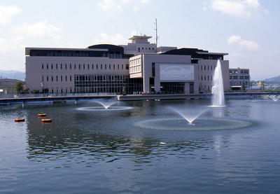 広々とした池の中の噴水の先にある寺田池オアシス広場の建物の外観写真