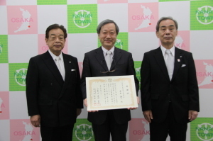 中央に賞状を持った若生先生、左に新田教育長、右に森田町長が立ち記念撮影をしている写真