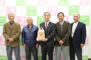 袋に入ったお米を持っている町長とかなんエコ米生産組合の方4名が並んで写っている写真