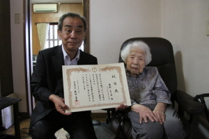 賞状を持った森田町長と町長の隣に座っている白髪の年配の女性の写真