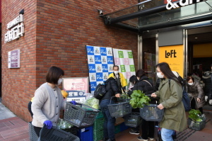 買い物かごを持ち、買い物をしている買い物客で賑わっているご当地野菜市の写真