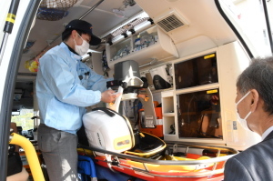 救急隊員が救急車の中で作業している様子を見ている町長の写真