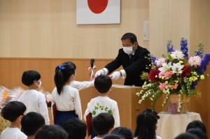 3人の園児が並び、1人の園児が修了証書を受け取っている写真
