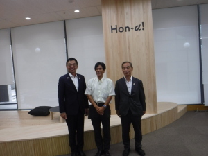「Hon+α！」と書かれた大きな柱の前に立ち記念撮影をしている南本千早赤阪村長、島田河内長野市長、森田町長の写真