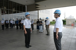 水色のヘルメットをかぶった男性2人が向かい合って立っている消防訓練の写真