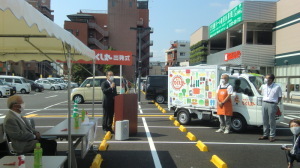 スーパー駐車場にて森田町長がマイクを持ち話をしている移動スーパー「とくし丸」出発式の写真
