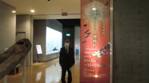 博物館内の「玉からみた古墳時代」と書かれた大きな看板の横に立っている森田町長の写真