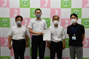 新田教育長、辞令交付書を持った玉川理事、森田町長、城田副町長が横一列に並んで記念撮影をしている写真